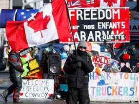 Une personne agite un drapeau canadien devant des banderoles en soutien aux camionneurs, à Ottawa, le 14 février 2022.