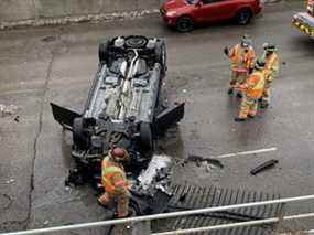 Les pompiers se tiennent près d'un SUV qui s'est retrouvé sur son toit sur la rue Wellington entre les rues Horton et York à Londres après s'être écrasé à travers deux clôtures métalliques et avoir traversé un mur lundi.  Le SUV est tombé à environ six mètres sur le trottoir en dessous.  Personne n'a été blessé, ont indiqué des responsables.  (Derek Ruttan/Le London Free Press)