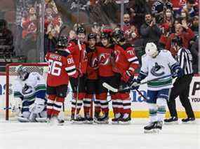 Le centre des Devils du New Jersey Yegor Sharangovich (17 ans) célèbre son but avec ses coéquipiers devant le gardien de but des Canucks de Vancouver Jaroslav Halak (41 ans) au cours de la première période au Prudential Center.