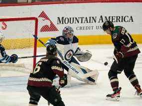 Le centre des Coyotes de l'Arizona Alex Galchenyuk (17) tente de marquer sur le gardien des Jets de Winnipeg Eric Comrie (1) au cours de la troisième période au Gila River Arena de Glendale, en Arizona, le 27 février 2022.