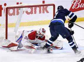 Adam Lowry des Jets marque contre le gardien des Canadiens Sam Montembeault mardi soir à Winnipeg.  Ce fut une soirée difficile pour Montembeault, qui a été retiré en troisième période après avoir accordé sept buts sur 23 tirs.