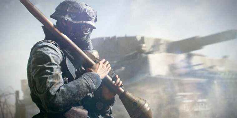 Assault class soldier holds a rocket while wearing a gas mask, with tank in background. From Battlefield 5