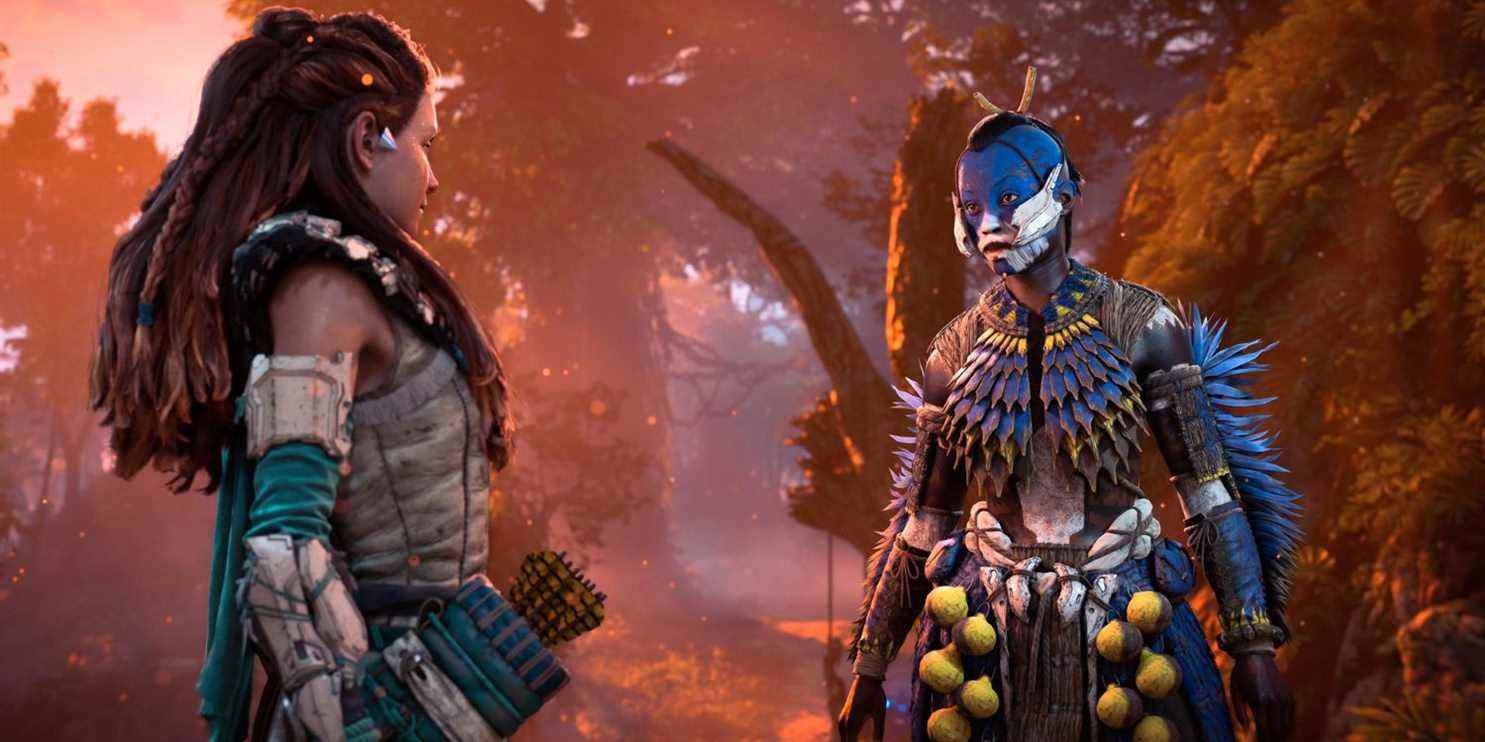 Aloy parlant à un soldat tenakth en armure bleue et jaune à plumes avec de la peinture faciale bleue et blanche