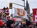 Un manifestant tient un drapeau Bitcoin lors d'une manifestation près de la colline du Parlement à Ottawa le 12 février 2022. 