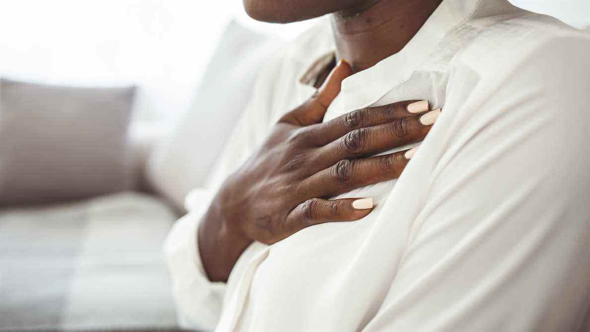 La femme dans la chemise blanche tient sa main au-dessus de son coeur