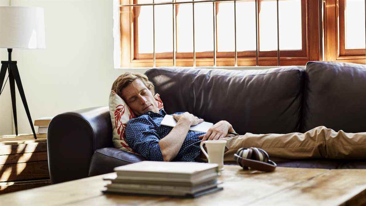 Homme faisant la sieste sur un canapé en cuir marron