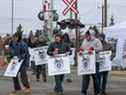 Dimanche, les travailleurs de CP Rail marchent sur une ligne de piquetage devant le siège social de l'entreprise à Calgary.  CP Rail a commencé à fermer ses portes pendant que les négociations se poursuivaient entre le syndicat et l'entreprise.