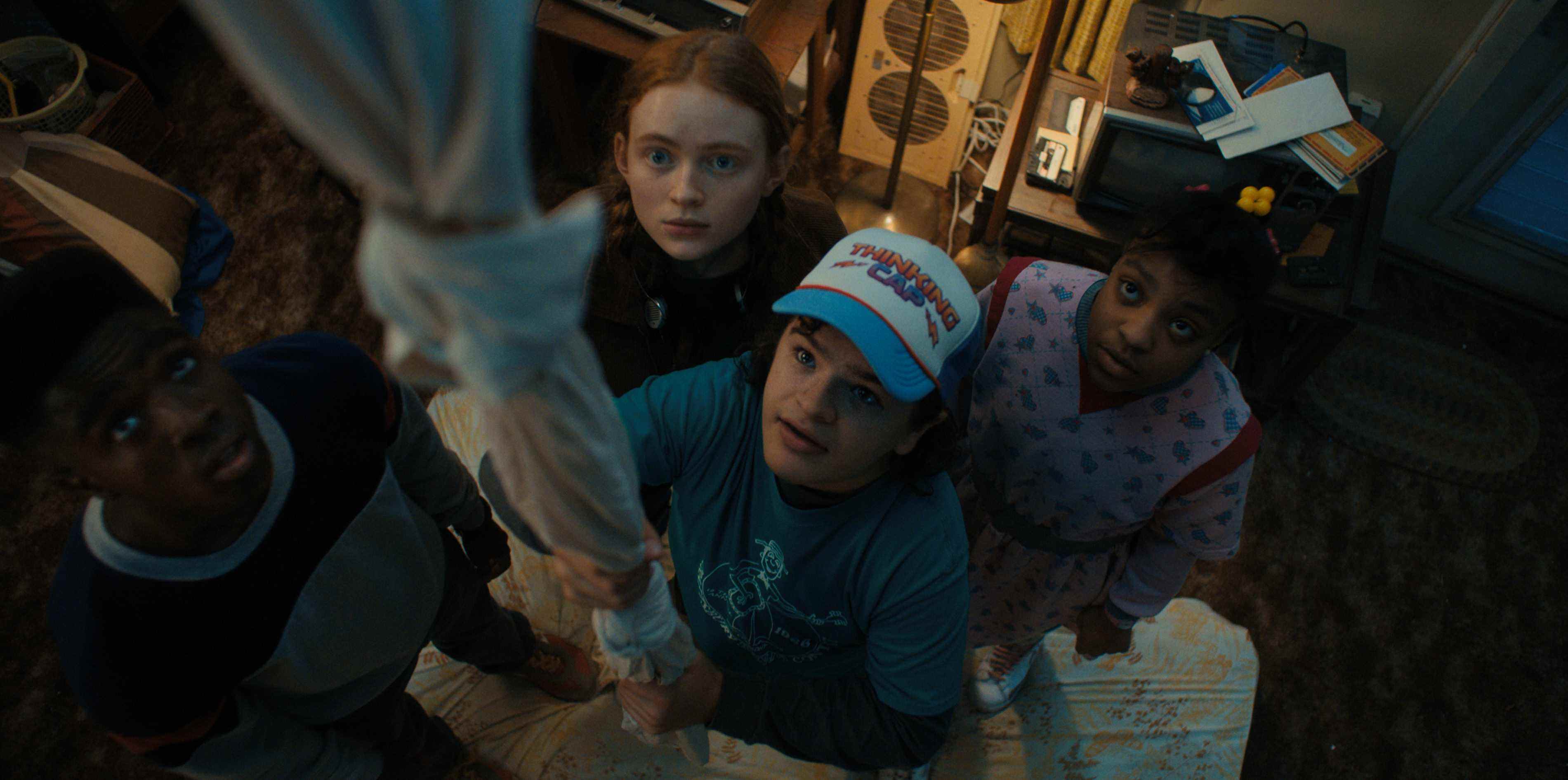 Lucas (Caleb McLaughlin), Max (Sadie Sink), Dustin (Gaten Matarazzo) et Erica (Priah Ferguson) regardent une image officielle de la saison 4 de Stranger Things