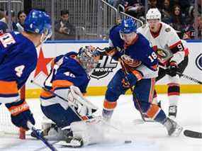 L'ailier gauche des Islanders de New York Anthony Beauvillier (18) défend le centre des Sénateurs d'Ottawa Josh Norris (9) contre une rondelle libre devant le gardien de but des Islanders de New York Semyon Varlamov (40) au cours de la première période à l'UBS Arena.