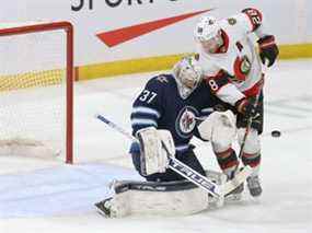 Le gardien de but des Jets Connor Hellebuyck effectue un arrêt avec l'attaquant des Sénateurs Connor Brown à sa porte lors du match de jeudi à Winnipeg.