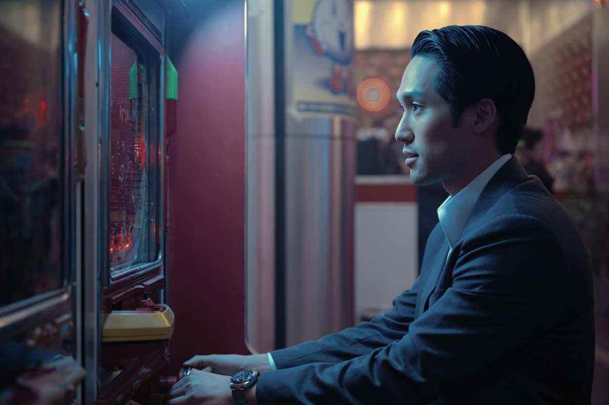 Soloman assis devant une machine à pachinko dans l'émission Apple TV Pachinko