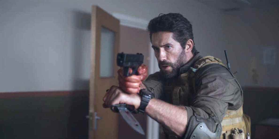 Scott Adkins dans le rôle de Jake Harris tenant un pistolet et un couteau dans One Shot.