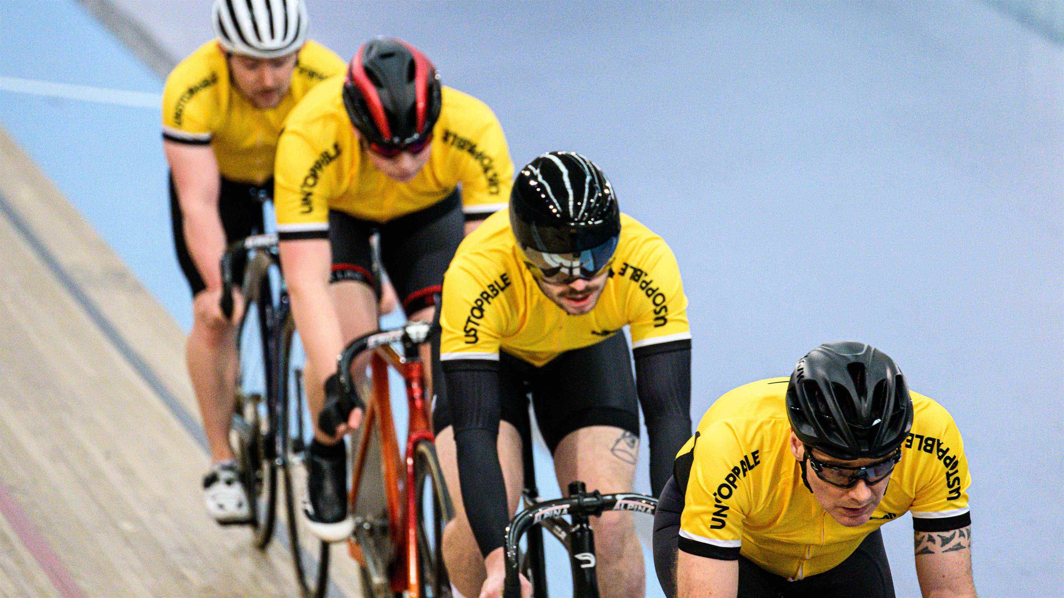 Quatre cyclistes circulant sur une piste de vélodrome