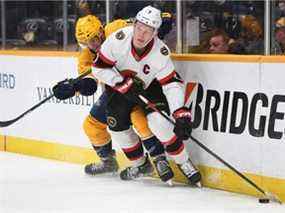 L'ailier gauche des Sénateurs d'Ottawa Brady Tkachuk cherche à passer la rondelle alors qu'il affronte le défenseur des Predators de Nashville Matt Benning en deuxième période au Bridgestone Arena.