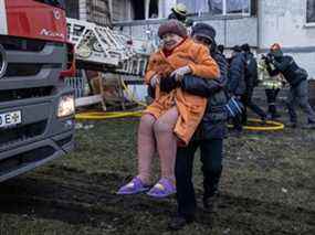 Un homme transporte une résidente âgée en lieu sûr après avoir été secourue par les pompiers d'un étage élevé d'un immeuble résidentiel après avoir été touché par une attaque russe aux premières heures du matin dans le district de Sviatoshynskyi le 15 mars 2022 à Kiev, Ukraine.