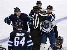 Wayne Simmonds (24 ans) des Maple Leafs de Toronto est retenu par des officiels alors qu'il tente de se rendre à Logan Stanley (64 ans) des Jets de Winnipeg lors de la troisième période d'action de la LNH à Winnipeg le 5 décembre 2021.