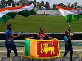 Les fans de cricket arborent les drapeaux de l'Inde (gauche, droite) et du Sri Lanka (au centre) avant un match test de cricket entre l'Inde et le Sri Lanka au stade Punjab Cricket Association (PCA) à Mohali le 3 mars 2022.