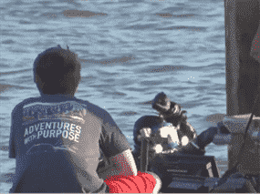 Plongeur dans l'eau avec quelqu'un assis sur le quai avec le dos tourné.