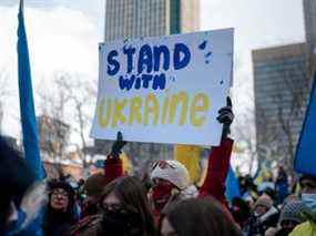 Une femme tient une pancarte alors que des membres de la communauté ukrainienne manifestent à la Place du Canada à Montréal, au Québec.