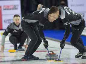 Le capitaine de l'équipe Wild Card 1, Brad Gushue, observe le premier Geoff Walker (à gauche) et le deuxième Brett Gallant (à droite) lors de la victoire de leur équipe contre l'équipe Wild Card 3 au Brier Tim Hortons de Lethbridge le 10 mars 2022.