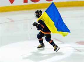 Le patineur de la Banque Scotia Jacob Paquet patine avec le drapeau de l'Ukraine avant le match de la LNH entre les Oilers d'Edmonton et les Canadiens de Montréal à Rogers Place à Edmonton, le samedi 5 mars 2022.