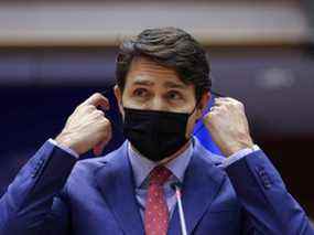 Le Premier ministre Justin Trudeau retire son masque facial pour s'adresser aux législateurs européens au milieu de l'invasion russe de l'Ukraine, à Bruxelles, Belgique, le 23 mars 2022.