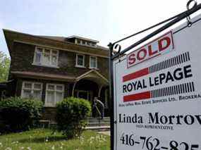 Un agent immobilier à vendre affiche à l'extérieur d'une maison qui avait été vendue à Toronto.