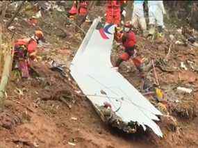 Cette capture d'écran prise le 24 mars 2022 à partir d'une vidéo de la chaîne de télévision publique China Central Television (CCTV) via AFPTV montre des équipes de secours avec un morceau du fuselage alors qu'elles poursuivent leurs recherches sur le site où un avion de ligne de l'Est de la Chine s'est écrasé sur un flanc de montagne près de Ville de Wuzhou dans la région méridionale du Guangxi en Chine.