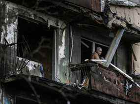 Un homme se tient sur le balcon d'un immeuble après qu'il a été bombardé à Kiev le 14 mars 2022.