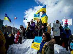 Un grand groupe de personnes s'est rassemblé devant l'ambassade de Russie à Sandy Hill, à Ottawa, pour s'unir aux Ukrainiens et protester contre l'invasion de l'Ukraine par la Russie, le dimanche 27 février 2022.