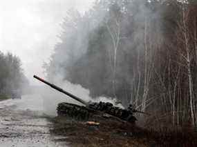 De la fumée s'échappe d'un char russe détruit par les forces ukrainiennes au bord d'une route dans la région de Lougansk le 26 février 2022.