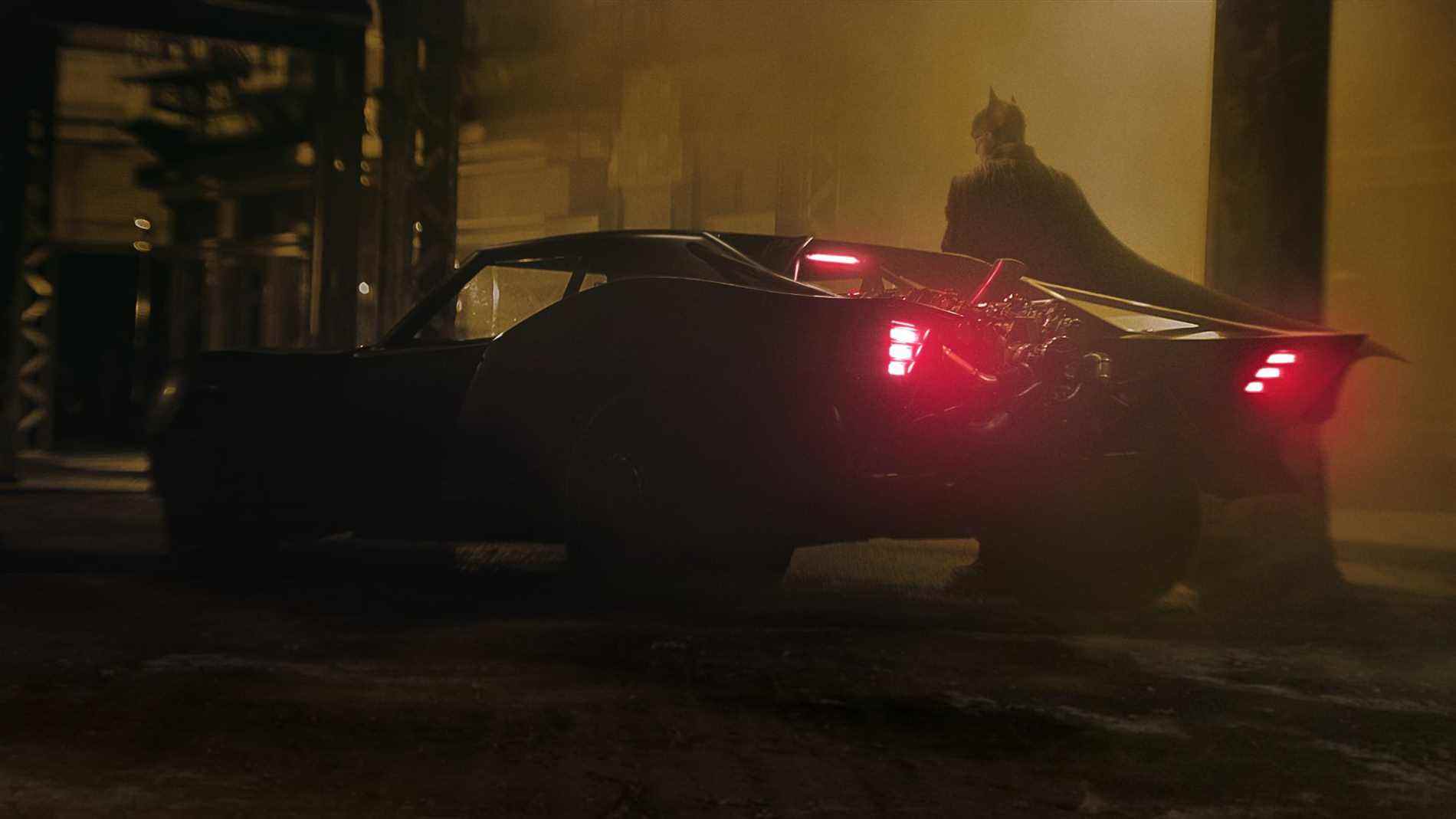 Le Batman debout à côté de la Batmobile