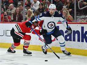 Pierre-Luc Dubois (80) des Jets de Winnipeg garde le contrôle de la rondelle alors que Jake McCabe (6) des Blackhawks de Chicago défend en troisième période le 20 mars 2022 au United Center de Chicago.  Winnipeg a battu Chicago 6-4.