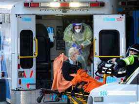 Les ambulanciers paramédicaux transfèrent un patient de leur ambulance au service des urgences de l'hôpital Michael Garron pendant la pandémie de COVID-19 à Toronto le lundi 10 janvier 2022.