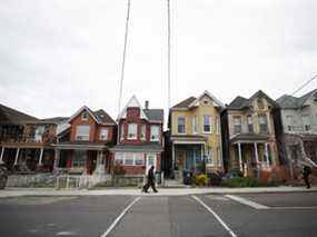 Des piétons passent devant des maisons à Toronto.