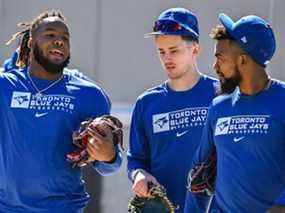 Vladimir Guerrero Jr., des Blue Jays de Toronto, à gauche, Cavan Biggio, au centre, et Teoscar Hernandez discutent alors qu'ils marchent vers un terrain d'entraînement lors d'un entraînement de printemps, le dimanche 13 mars 2022, à Dunedin, en Floride.