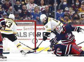 Le centre des Bruins de Boston Trent Frederic (11) marque sur le gardien des Jets de Winnipeg Connor Hellebuyck (37) en deuxième période au Canada Life Centre à Winnipeg le vendredi 18 mars 2022.