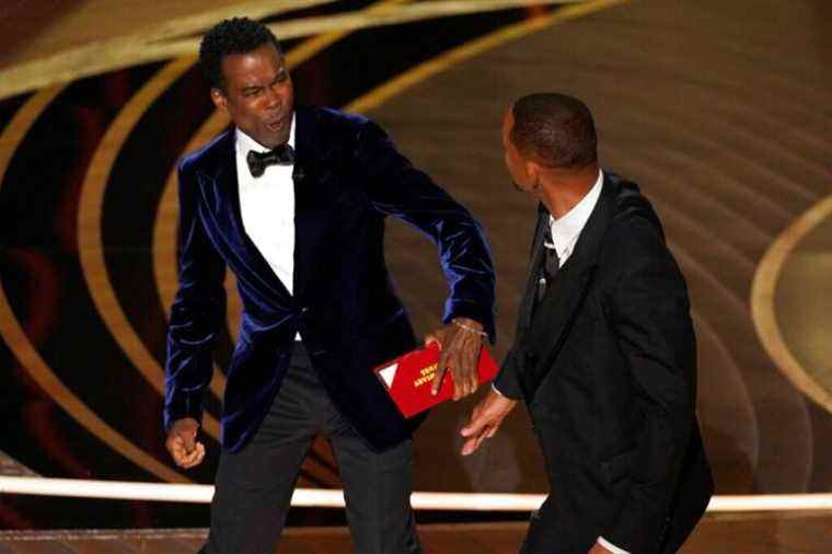 presenter Chris Rock, left, reacts after being hit on stage by Will Smith while presenting the award for best documentary feature at the Oscars on Sunday, March 27, 2022, at the Dolby Theatre in Los Angeles. (AP Photo/Chris Pizzello)