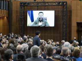 Le président ukrainien Volodymyr Zelenskyy pose sa main sur sa poitrine en écoutant le premier ministre canadien Justin Trudeau prononcer son discours d'ouverture avant de s'adresser au Parlement canadien le mardi 15 mars.