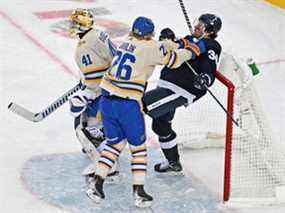 Le défenseur des Sabres de Buffalo Rasmus Dahlin (à gauche) pousse le tireur d'élite des Maple Leafs de Toronto Auston Matthews dans le filet derrière le gardien Craig Anderson lors de la Classique Héritage dimanche au Tim Hortons Field.