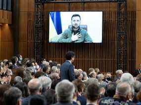 Le président ukrainien Volodymyr Zelenskyy pose sa main sur sa poitrine en écoutant le premier ministre canadien Justin Trudeau prononcer son discours d'ouverture avant de s'adresser au Parlement canadien, mardi 15 mars à Ottawa.  LA PRESSE CANADIENNE/Adrian Wyld