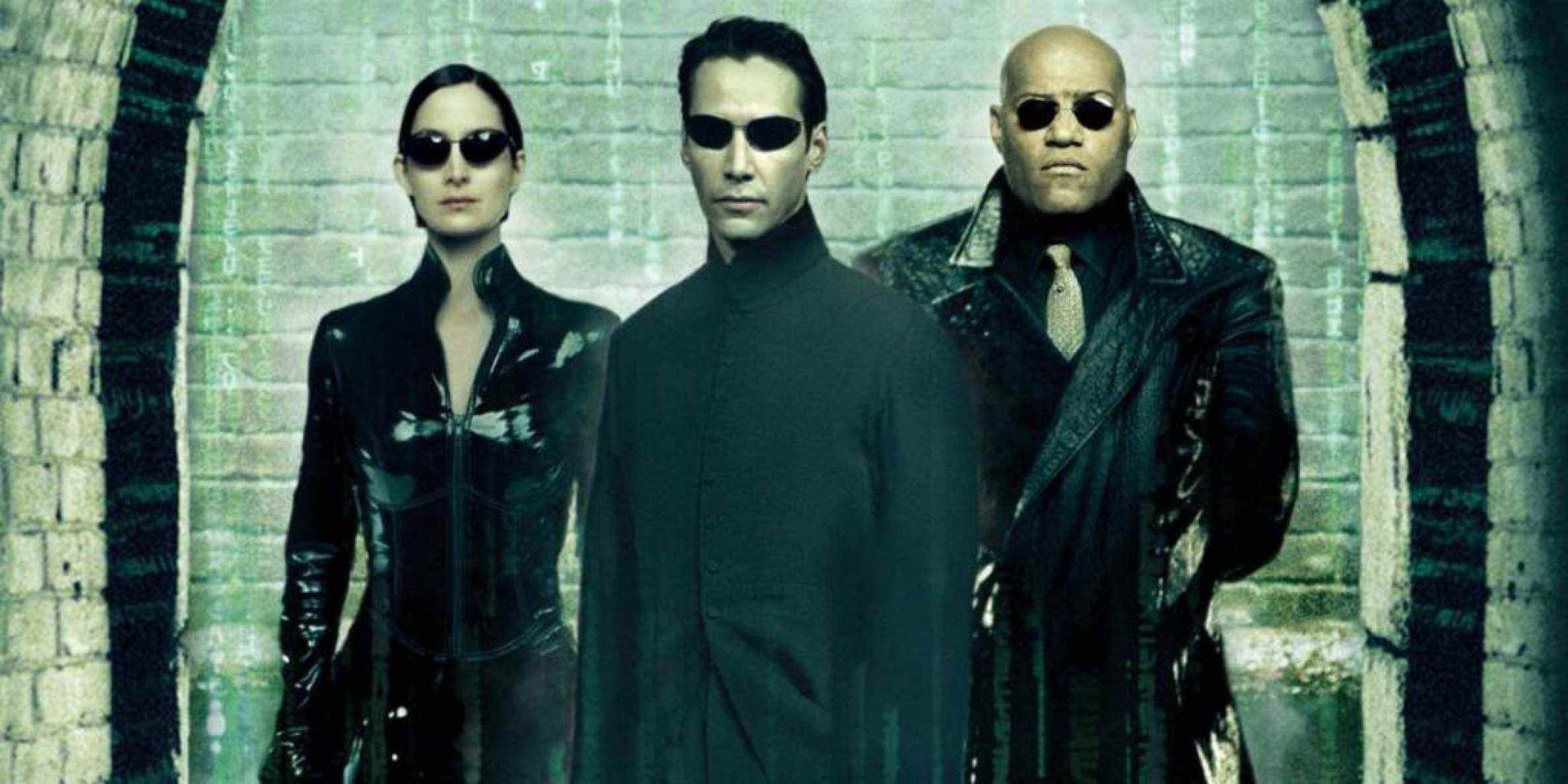 Trinity, Neo et Morpheus de Matrix posent devant un mur avec des chiffres verts en arrière-plan