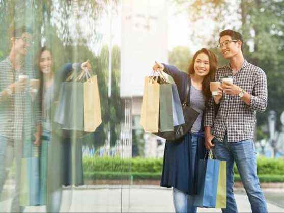 Souriante jeune femme montrant quelque chose d'intéressant dans la vitrine de son petit ami