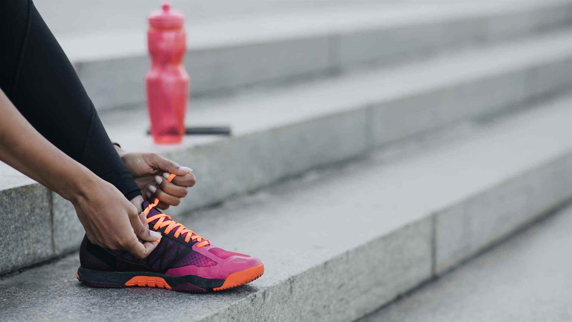 Personne attachant des lacets de chaussures avec une bouteille d'eau à proximité