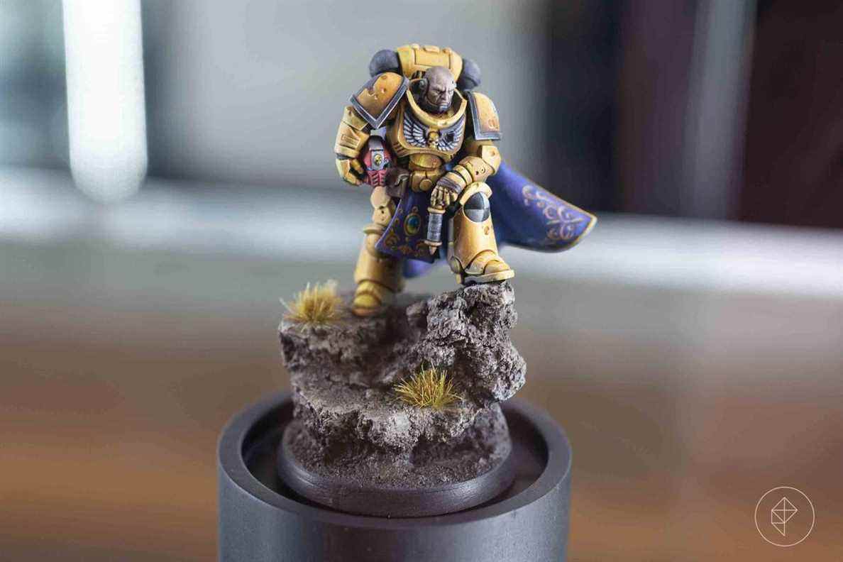 Un Space Marine en jaune, son armure entachée par la bataille.