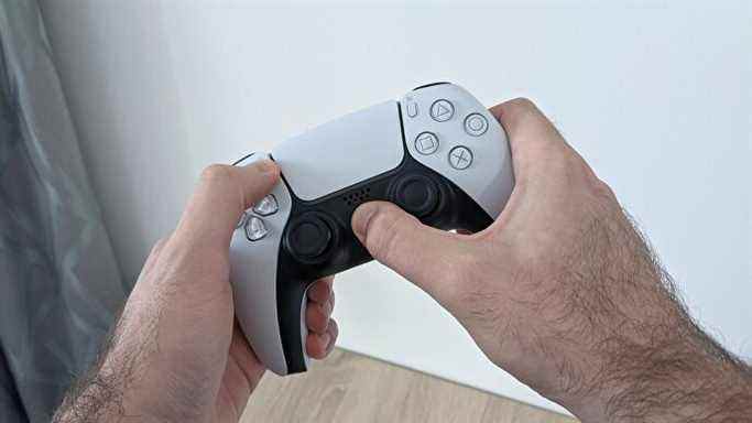 Une manette PS5, les mains de l'utilisateur maintenant enfoncées les touches PS et Partager pour lancer l'appairage Bluetooth.