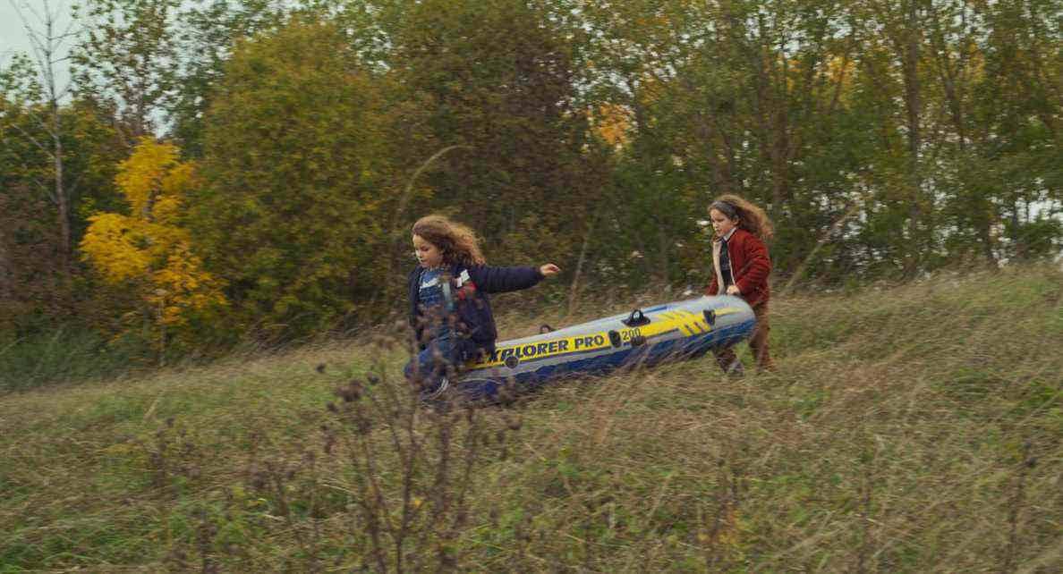 Nelly et sa mère, toutes les deux du même âge, courent dans la forêt avec un radeau gonflable à Petite Maman