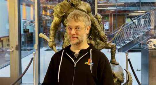 Cory Barlog stood in front of a statue of Kratos and Atreus