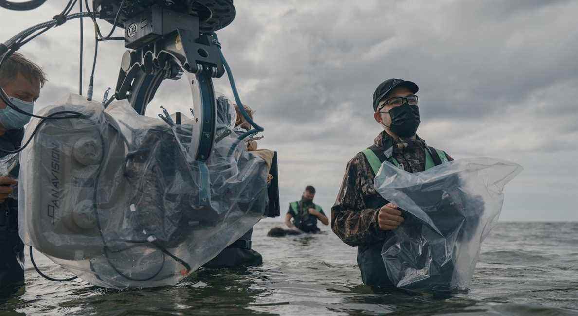 Le réalisateur Robert Eggers, dans l'eau jusqu'aux hanches et tenant une caméra enveloppée de plastique, sur un tournage pour The Northman