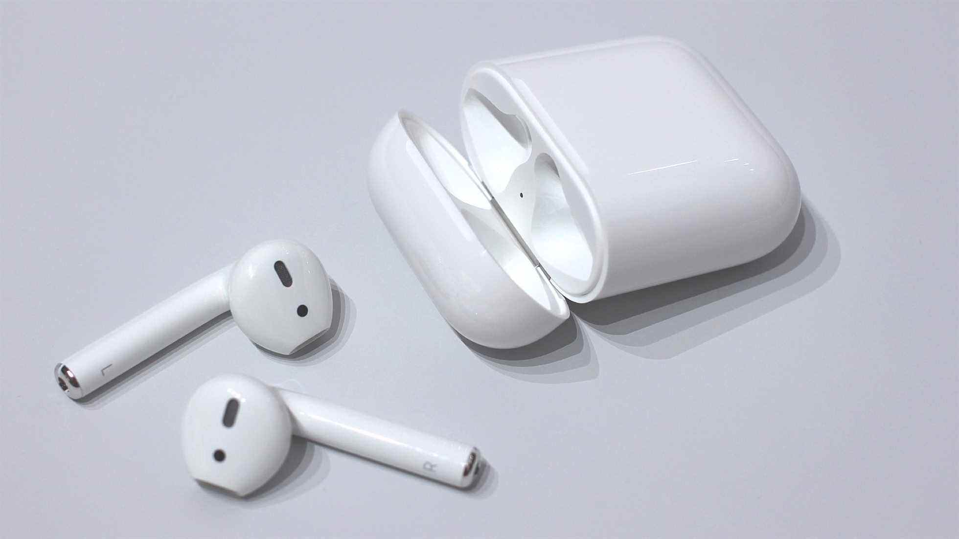 une paire d'airpods avec leur boitier de charge